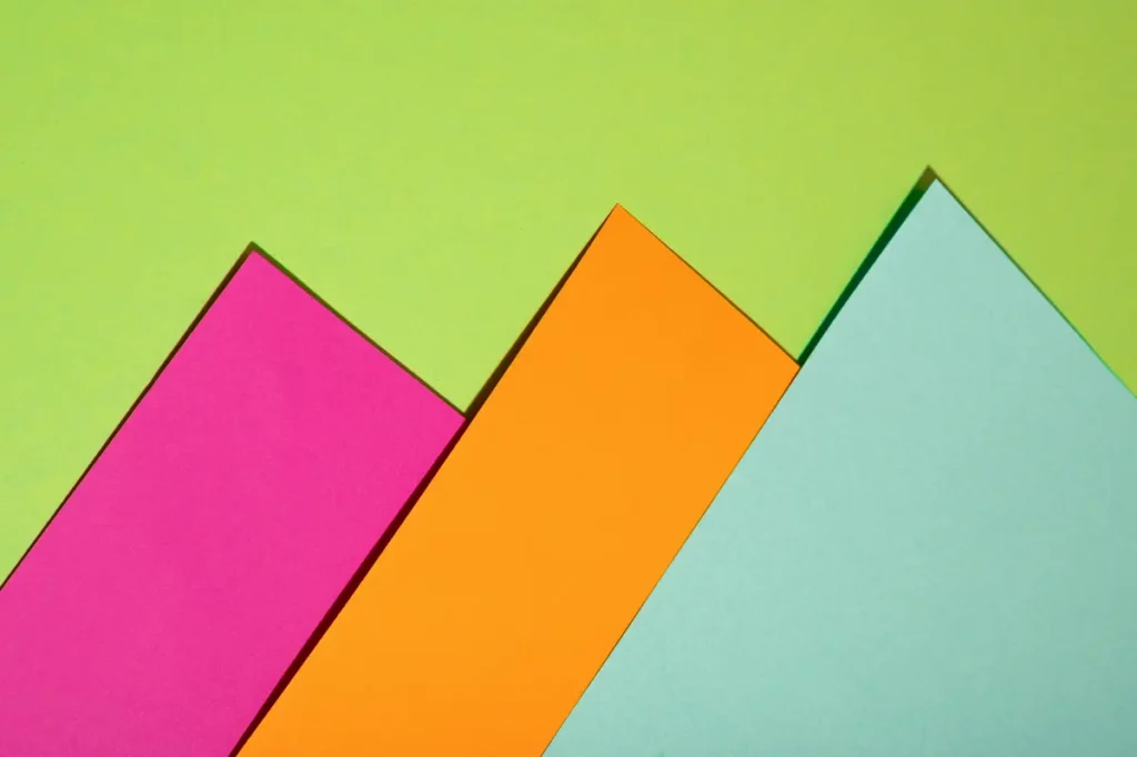 Illustration représentant 3 feuilles de couleurs formant des montagnes sur un fond uni vert